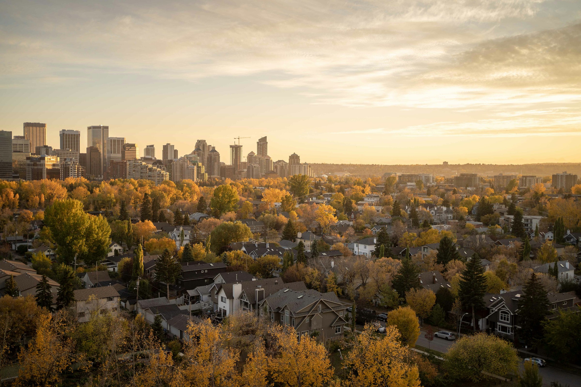 Calgary skyline and river valley at sunset with mountains in the background