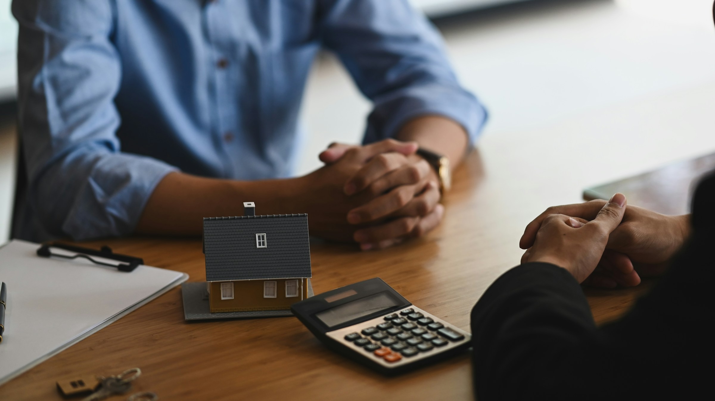 Mortgage affordability consultation with model house, calculator, and house keys on desk