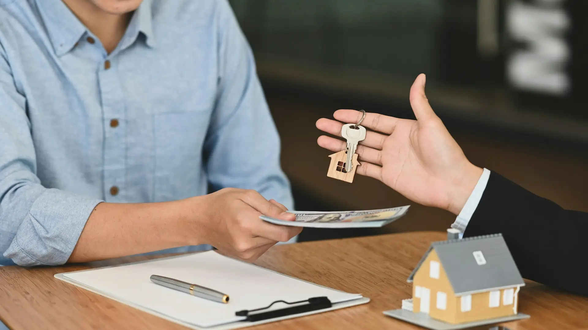 Mortgage broker handing house keys to a new homebuyer at closing